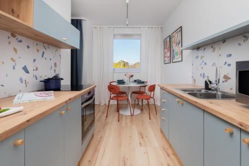 a kitchen with white cabinets and a table with chairs at Retro Style Apartment with Balcony near the Forest by Noclegi Renters in Gdynia