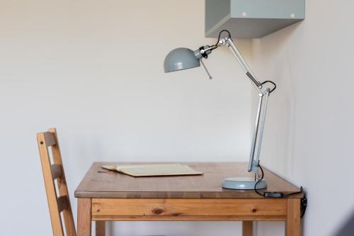 a desk with a lamp on top of a wooden table at Retro Style Apartment with Balcony near the Forest by Noclegi Renters in Gdynia