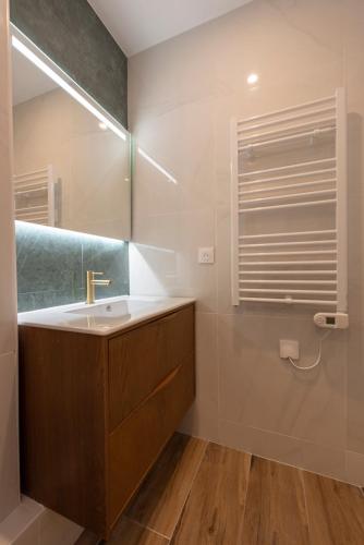 une salle de bain avec un lavabo et un miroir dans l'établissement Au pied de la Tour, à Paris