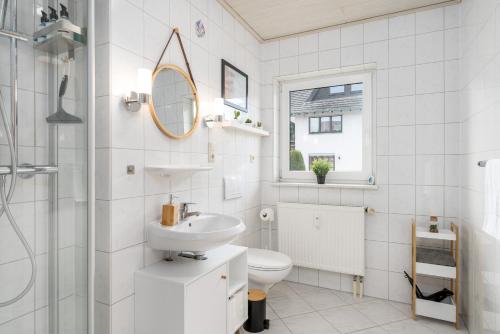 a white bathroom with a sink and a toilet at Harmony: Edersee Apartment – Sperrmauer – Lounge in Edersee