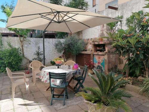 stół i krzesła z parasolem na patio w obiekcie B&B Il Giardinetto Alghero w mieście Alghero