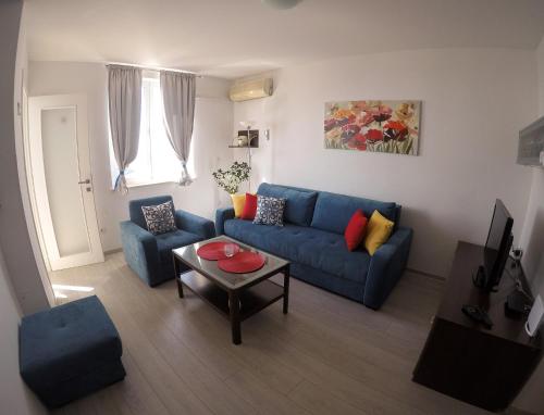 Una sala de estar con un sofá azul y una mesa. en Apartment Precious View, en Dubrovnik