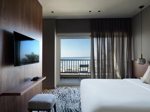 ピタゴリオにあるDoryssa Seaside Resortのベッドと大きな窓が備わるホテルルームです。