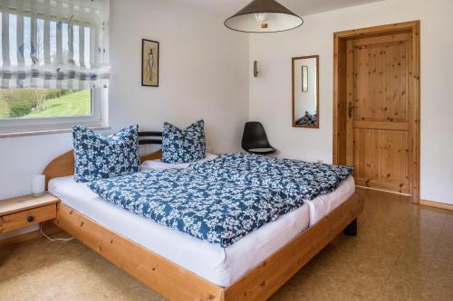 een slaapkamer met een bed met blauwe kussens en een raam bij Gutjahr in Freiamt