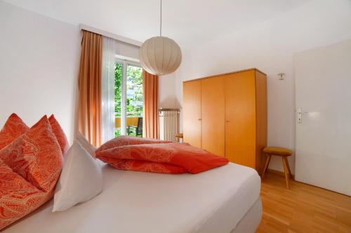1 dormitorio con 1 cama con almohadas de color naranja y blanco en Villa Sabine - Edith, en Merano
