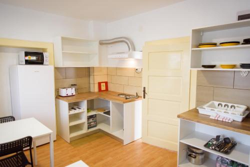a small kitchen with white cabinets and a white refrigerator at Wheelinger Homestay in Păuleni-Ciuc