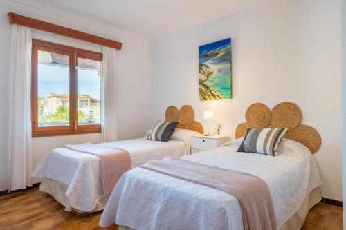 zwei Betten in einem weißen Zimmer mit Fenster in der Unterkunft Mar i Cel in Colònia de Sant Pere