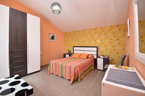 1 dormitorio con cama y pared amarilla en Villa Victoria, en Cádiz