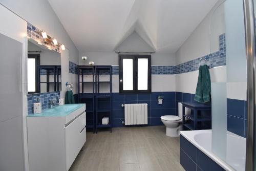 baño azul y blanco con bañera y aseo en Villa Victoria, en Cádiz