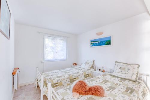 a white bedroom with two beds and a window at Beau T3 au mont des oiseaux in Hyères