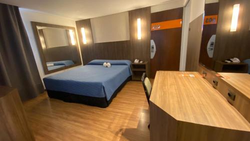 a bedroom with a blue bed and a mirror at Afford Hotéis in Lages