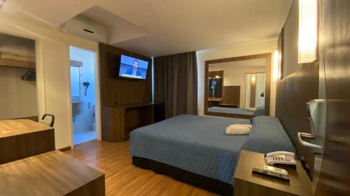 a hotel room with a bed and a television at Afford Hotéis in Lages