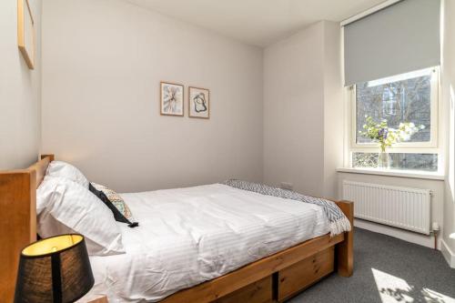 una camera da letto con un letto con lenzuola bianche e una finestra di West End @ Netflix @ Newly Built ad Aberdeen