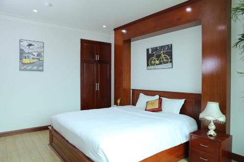 a bedroom with a large white bed with a wooden headboard at Thành Vinh Hotel & Apartment in Ho Chi Minh City