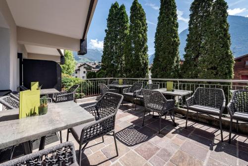 a group of chairs and tables on a patio with trees at Vitaurina Royal Hotel in Molini di Tures