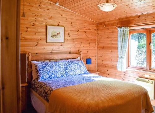 een slaapkamer met een bed in een blokhut bij Secluded Pine Lodge 2 in Wigton