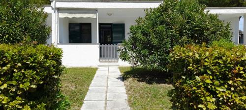 a white house with green bushes and a walkway at Ibiscus Beach Village in Follonica