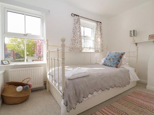 a bedroom with a bed and two windows at Victoria Cottage in Saxmundham
