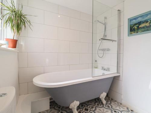 a white bathroom with a tub and a toilet at Victoria Cottage in Saxmundham