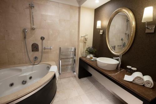 a bathroom with a tub and a sink and a mirror at Agaoğlu My City Hotel Istanbul in Istanbul