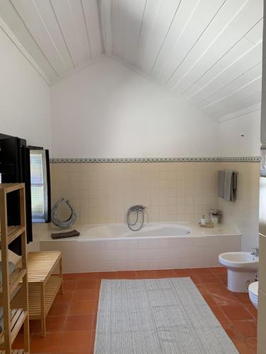 uma grande casa de banho com banheira e WC em Monte do Pereiro em Santiago do Cacém