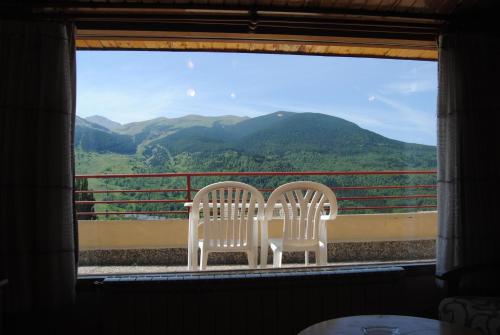 two white chairs sitting next to a window with mountains at Apartamentos SNÖ Edelweiss in Cerler