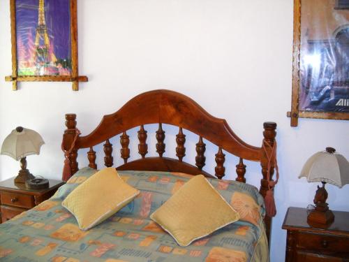 una camera con letto in legno e 2 comodini di Hotel Aeropuerto Monte Grande a Monte Grande