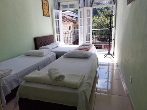 three beds in a room with a window at Pousada Souza Castro in Ouro Preto