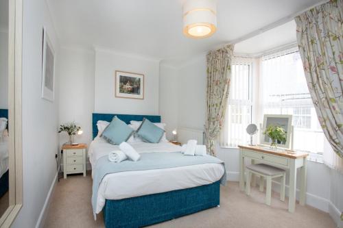 a bedroom with a bed and a desk and a window at Holmdale House in Sidmouth