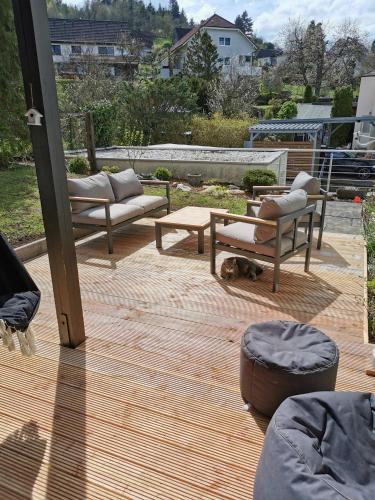 a patio with couches and a dog laying on a wooden deck at Ferienwohnung in Waldrandlage in Nationalpark Schleiden / Eifel in Schleiden