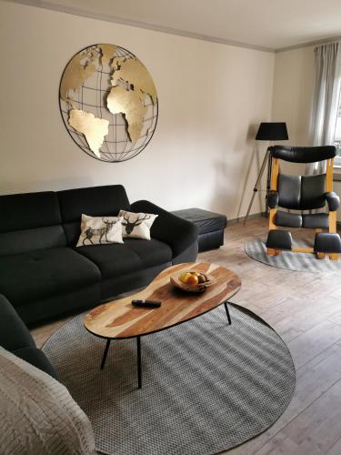 a living room with a black couch and a wooden coffee table at Ferienwohnung in Waldrandlage in Nationalpark Schleiden / Eifel in Schleiden