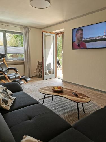 a living room with a couch and a tv on the wall at Ferienwohnung in Waldrandlage in Nationalpark Schleiden / Eifel in Schleiden