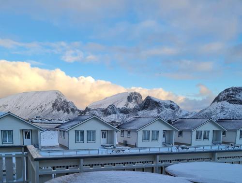 a row of houses in front of snowy mountains at Lofoten Værøy Bryggehotell AS in Værøy
