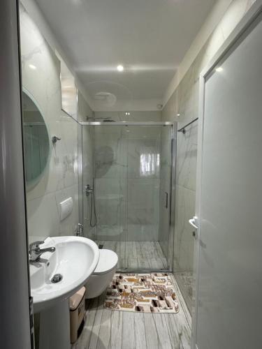 een badkamer met een douche, een toilet en een wastafel bij Vila Kylie in Ksamil
