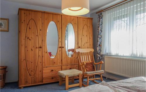 a bedroom with a wooden closet with a chair and mirror at 3 Bedroom Lovely Home In Schortens in Schortens