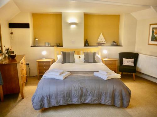 a bedroom with a large bed and a chair at Talehay Cottages in Looe