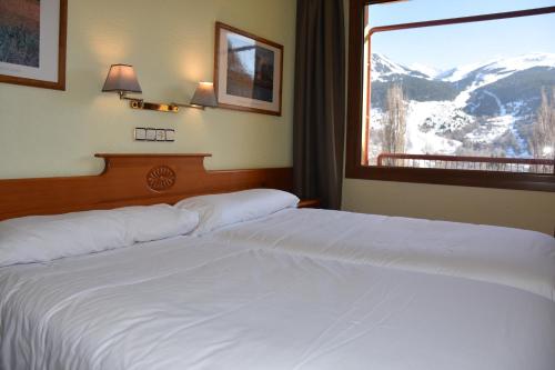 a hotel room with two beds and a large window at Apartamentos SNÖ Edelweiss in Cerler