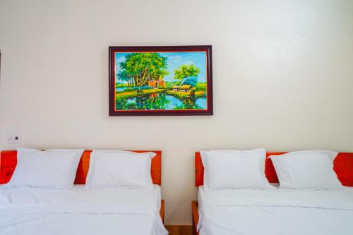 2 weiße Betten in einem Zimmer mit einem Bild an der Wand in der Unterkunft Phong Nha Magic Fingers Homestay and Spa in Phong Nha