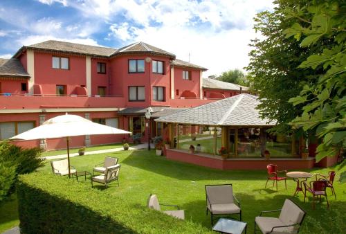 a hotel with chairs and an umbrella in the yard at Hotel Del Lago in Puigcerdà