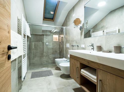 ein Bad mit einer Dusche, einem WC und einem Waschbecken in der Unterkunft Piciulei Grant in Wolkenstein in Gröden