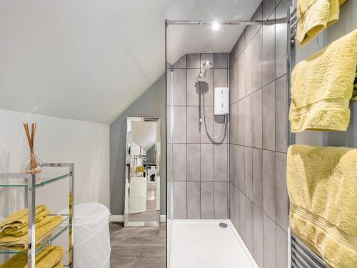 uma casa de banho com um chuveiro e toalhas amarelas em The View em West Stow