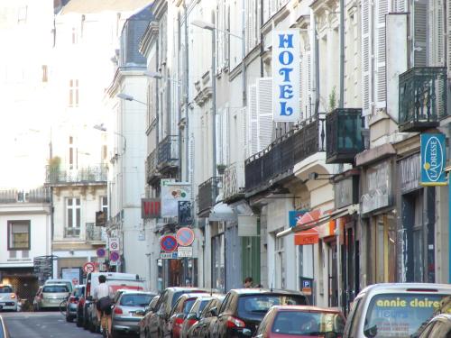 una concurrida calle de la ciudad con coches aparcados en la calle en Hotel Des Lices - Angers, en Angers