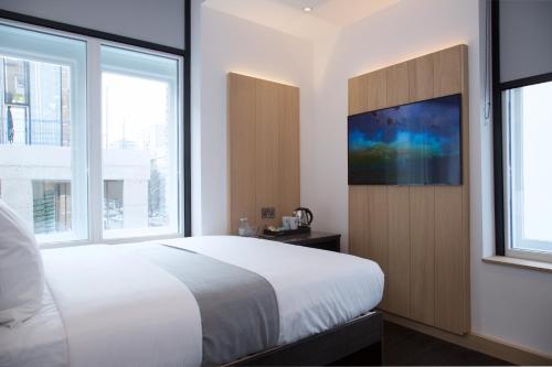 a bedroom with a large bed and a flat screen tv at The Z Hotel Shoreditch in London