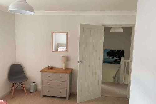 a bedroom with a door and a dresser and a mirror at Dunes View, waterside home with stunning views. in Bembridge