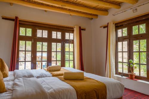 een slaapkamer met een groot bed en 2 ramen bij Likir Pottery Homestay - Likir Village - Sham Valley in Leh