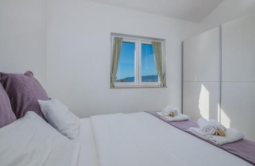 Cette chambre blanche dispose d'un lit et d'une fenêtre. dans l'établissement Wabi Sabi Resort & Apartments, à Krk