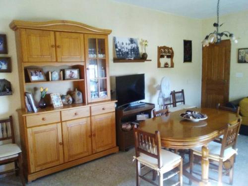 a dining room with a wooden table and a television at La caseta d'Amparo in Catadau