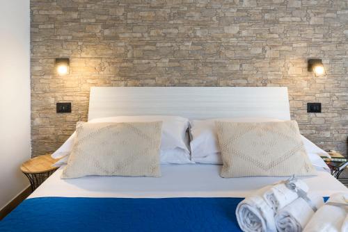 a white bed with two pillows and a brick wall at Il Tempio di Athena - Cultura e Relax a Siracusa in Siracusa