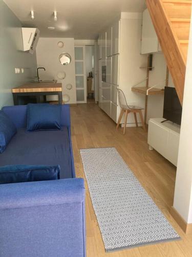 ein Wohnzimmer mit einem blauen Sofa und einer Küche in der Unterkunft Appartement duplex chaleureux in Dammartin-en-Goële