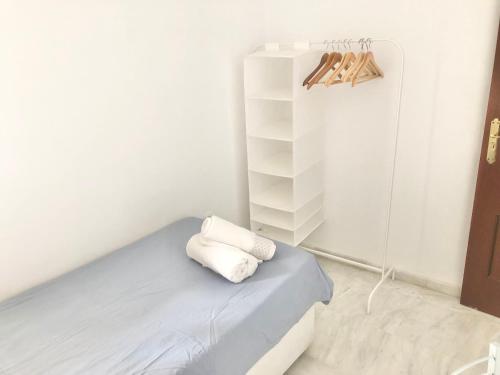 a bedroom with a bed with white walls and a shelf at Maravilloso alojamiento en pleno centro de Dos Hermanas in Dos Hermanas